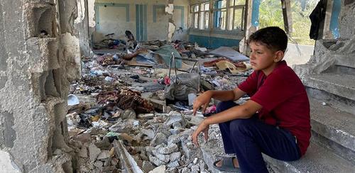 Image: Boy sitting in the rubble of a destroyed UNRWA school in Nuseirat, Middle Areas, Gaza 2024. Credit: UNRWA