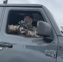 ICE agent points riot gun at motorist filming him. Image from video short, The Arizona Republic...